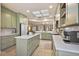 Bright kitchen showcasing an island with marble countertops, light-green cabinets, and open floor plan at 13096 Se 93Rd Terrace Road, Summerfield, FL 34491