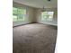 Bright living room featuring neutral carpet, large windows, and a decorative chandelier at 15 Clear Way, Ocala, FL 34472