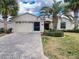 Attractive home showcasing a brick paver driveway, a two-car garage, and manicured landscaping with mature palms at 15857 Sw 11Th Terrace Rd, Ocala, FL 34473