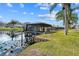 Waterfront home features a covered boat dock and lift on a picturesque lake with lily pads and bright blue sky at 1621 Yellow Brick Rd, Astor, FL 32102