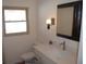 Bright bathroom featuring a toilet, quartz vanity top, sink, vintage style lighting and large, dark framed mirror at 3560 Sw 24Th Avenue Rd, Ocala, FL 34471