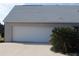 Attached two-car garage featuring a white door, concrete driveway, and mature landscaping at 3560 Sw 24Th Avenue Rd, Ocala, FL 34471