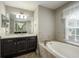 Bright bathroom with a soaking tub, a dark wood vanity, granite counters, and tile floors at 4604 Se 33Rd Pl, Ocala, FL 34480