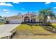 Inviting single-story home featuring a manicured front lawn, complemented by a two-car garage and palm tree at 6188 Sw 84Th St, Ocala, FL 34476