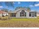 Home's backyard featuring large windows for natural light, green grass, and an enclosed lanai at 6793 Sw 111Th Loop, Ocala, FL 34476