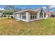 Home's backyard featuring multiple windows for natural light, an efficient AC unit, and green grass at 6793 Sw 111Th Loop, Ocala, FL 34476