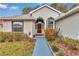 A well-maintained home featuring an inviting red front door, flanked by decorative landscaping and symmetrical windows at 6793 Sw 111Th Loop, Ocala, FL 34476