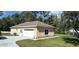 View of the home's back exterior and garage, featuring a well-maintained lawn and landscaping at 8498 Sw 129Th Terrace Rd, Dunnellon, FL 34431