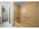 Bathroom featuring a yellow tiled bathtub and shower, tile floors, and a doorway leading to the hallway at 8973 Sw 104Th Ln, Ocala, FL 34481