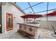 Covered patio featuring an outdoor kitchen, a stainless steel grill, and a red-framed glass door at 9276 Sw 89Th St Rd, Ocala, FL 34481