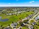 Scenic aerial view of a home nestled within a lush community, showcasing golf course and serene pond at 9884 Se 175Th Pl, Summerfield, FL 34491