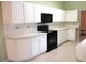 Well-lit kitchen featuring white cabinetry, black appliances, and tiled floor at 11353 Sw 138Th Ln, Dunnellon, FL 34432