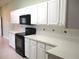 Bright kitchen with white cabinets, black appliances, and tiled backsplash at 11353 Sw 138Th Ln, Dunnellon, FL 34432