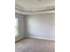 A bright, carpeted bedroom, featuring a ceiling with crown molding and a view to the outside at 120 Dogwood Drive Cir, Ocala, FL 34472