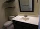 This bathroom has a vanity with countertop sink, a toilet, and shelving above at 14180 Se 53Rd Ave, Summerfield, FL 34491