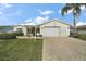 Inviting one-story home showcases a brick-paved driveway and lush green lawn complemented by a mature palm tree at 2538 Privada Dr, The Villages, FL 32162
