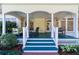 Charming front porch with seating, white columns, and painted blue floor with verdant landscape at 2775 Sw 53Rd St, Ocala, FL 34471