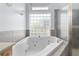 Bright bathroom features a large soaking tub with jets and a glass block window for natural light at 32 Allenwood Look, Ormond Beach, FL 32174