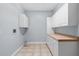This laundry room has tile floors, with white cabinets and countertop space for folding at 32 Allenwood Look, Ormond Beach, FL 32174