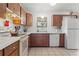 Traditional kitchen featuring wood cabinetry, white appliances, tile countertops, and a bright window over the sink at 48 Pine Trace Loop, Ocala, FL 34472