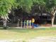 Playground located in a community area with mature trees and shaded seating at 55 Sw Fig Tree Ln, Dunnellon, FL 34431