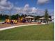 Community playground featuring colorful play structures, green grass, and shade pavilions at 55 Sw Fig Tree Ln, Dunnellon, FL 34431