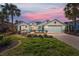 Charming single-story home featuring a well-manicured lawn, brick driveway, two-car garage, and a beautiful sunset sky at 8826 Sw 83Rd Cir, Ocala, FL 34481