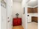 Hallway with hardwood floors and a red accent cabinet leads to a laundry room at 9581 Sw 63Rd Loop, Ocala, FL 34481