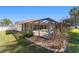 A view of the backyard with a screened-in pool, tropical landscaping, and well-maintained lawn at 10080 Se 68Th Ct, Belleview, FL 34420