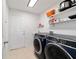 Neat laundry room with modern appliances, ample shelving, and a utility sink at 10080 Se 68Th Ct, Belleview, FL 34420