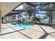 Screened in swimming pool features concrete flooring, beautiful trees, and lush landscaping at 10080 Se 68Th Ct, Belleview, FL 34420