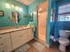 Stylish teal bathroom featuring tile floors, a shower, a large vanity with storage, and a matching mirror at 10823 Sw 83Rd Ave, Ocala, FL 34481