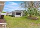 Back exterior featuring a screened-in porch and lush green lawn with a tree at 11221 Sw 71St Ct, Ocala, FL 34476