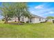 Green backyard featuring a lush lawn, mature tree, and sliding glass door at 11221 Sw 71St Ct, Ocala, FL 34476