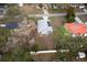 An aerial view of the single Gathering home with grey roof, screened-in porch, and mature trees at 12164 Se 85Th Ct, Belleview, FL 34420