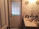 Bathroom with patterned wallpaper, a sink, and a door with blinds at 12330 Sw 43 St Rd, Ocala, FL 34481