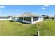 A view of the rear of the property highlighting the screened lanai with lush green lawn at 17755 Se 117Th Cir, Summerfield, FL 34491