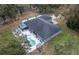 An aerial view of backyard pool and outdoor entertaining area, surrounded by lush green trees at 2045 Marion County Rd, Weirsdale, FL 32195