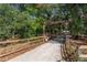 A gated driveway entrance has a wood frame and fence with lush greenery, enhancing privacy and curb appeal at 2045 Marion County Rd, Weirsdale, FL 32195