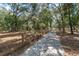 A long concrete driveway lined with a wooden fence winds through a canopy of lush green trees at 2045 Marion County Rd, Weirsdale, FL 32195