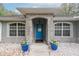 Inviting front entryway with blue door, stone facade, decorative planters, and updated details at 2045 Marion County Rd, Weirsdale, FL 32195