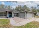 Well-kept home with a two car garage, blue door, concrete walkway and beautiful plants at 2045 Marion County Rd, Weirsdale, FL 32195