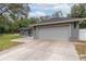 Two car garage with concrete driveway on a well maintained home with grass and a small fence at 2045 Marion County Rd, Weirsdale, FL 32195