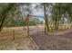 Wooden gate with a metal opening and fenced pasture showcasing the property's border at 2045 Marion County Rd, Weirsdale, FL 32195