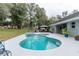 Backyard with a kidney-shaped pool, attached spa, and covered outdoor seating, perfect for summer relaxation at 2045 Marion County Rd, Weirsdale, FL 32195