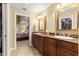 Primary bathroom featuring double sinks, granite counters, wood cabinets, and a view to the bedroom and walk-in closet at 2840 Se 35Th St, Ocala, FL 34471