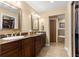 Bathroom featuring double sinks, granite counters, wood cabinets, tub, tiled floors, and walk-in closet at 2840 Se 35Th St, Ocala, FL 34471