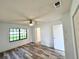 Bright bedroom featuring wood-look floors, ceiling fan, a window and a doorway at 301 Oak Track Way, Ocala, FL 34472