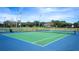 View of a well-maintained tennis court surrounded by lush greenery and fencing on a sunny day at 3999 Sw 51St Ct, Ocala, FL 34474