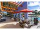 Covered patio with picnic tables and red umbrellas near the pool area, perfect for outdoor dining at 4555 Sw 52Nd Cir # 103, Ocala, FL 34474